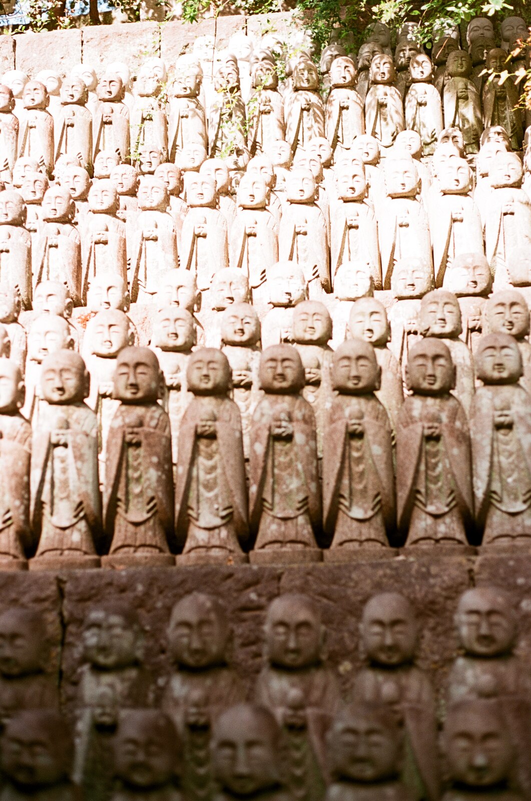 Rangées de statuettes jizo en pierre alignées sur un talus